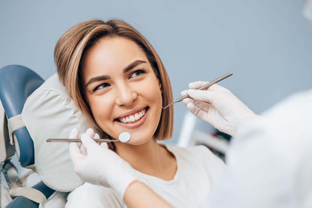 Portrait of a young blonde woman receiving periodontal therapy during a dental examination in Washington, MO.