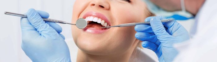 A young female patient receiving periodontal therapy at a dental office, with a focus on molar treatment.